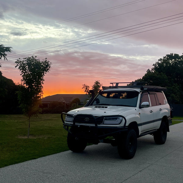 White SUV parked on a driveway with a sunset sky in the background